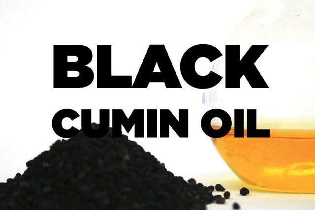 A black cumin oil is sitting next to some other things.